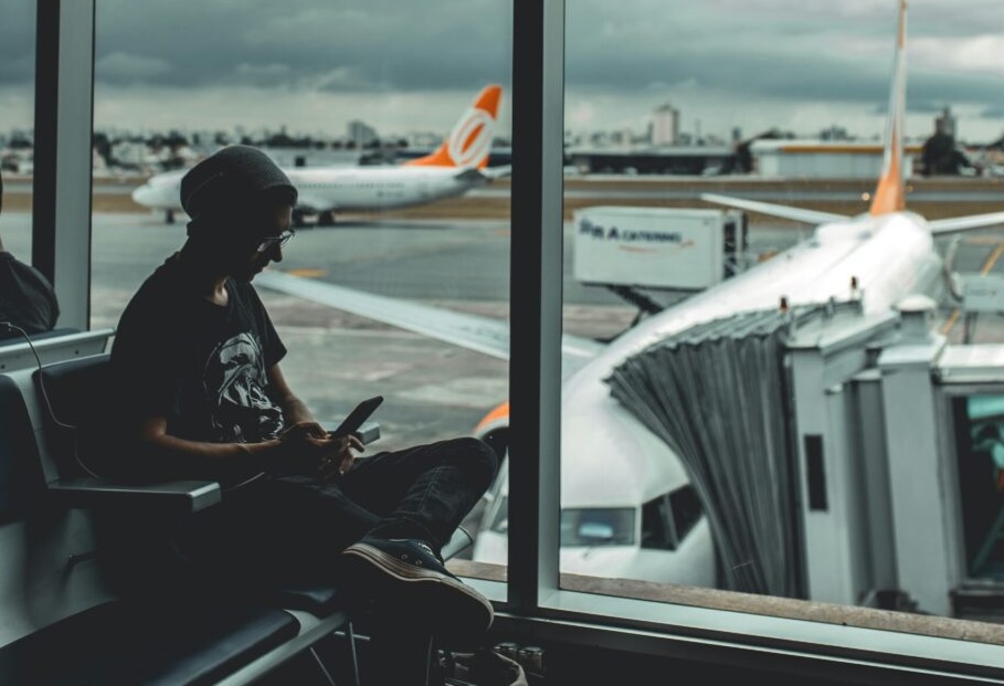 Person som sitter ved et vindu på en flyplass og venter. 