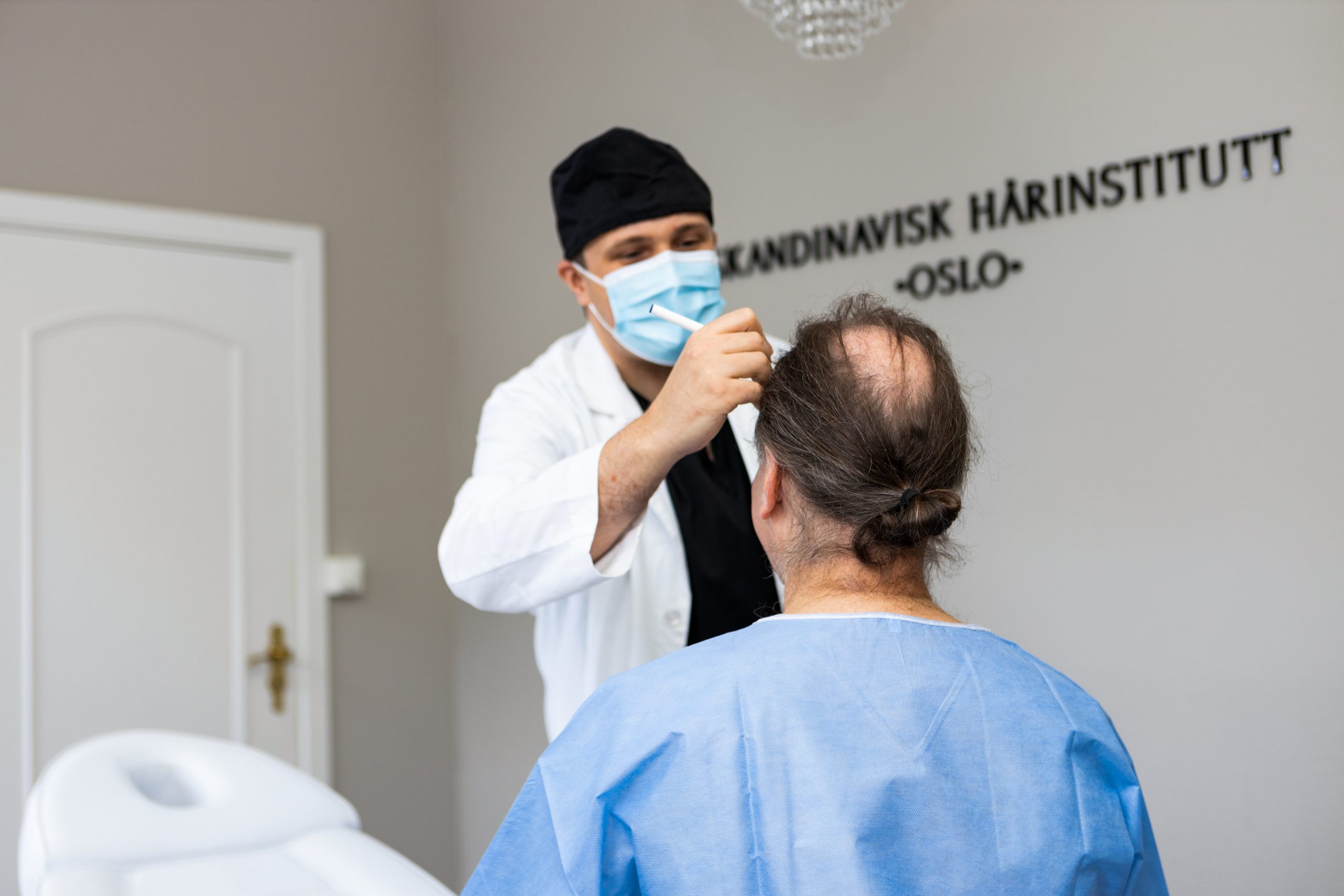 En kirurg som skisserer på hodet til pasient, hvor han skal operere. Pasienten har lite hår på hode.