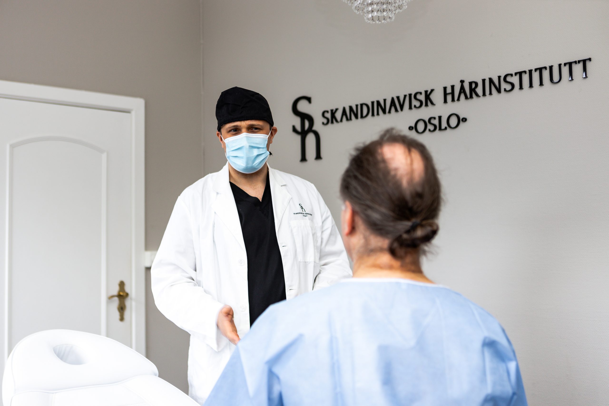 Hårkirurg som prater med pasient før hårtransplantasjon.